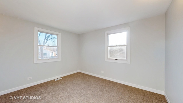 unfurnished room with carpet floors, visible vents, and baseboards