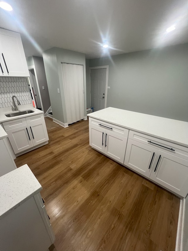 kitchen with white cabinetry, sink, hardwood / wood-style floors, and backsplash