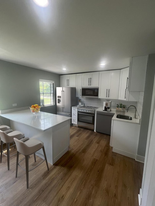 kitchen featuring sink, dark wood-type flooring, appliances with stainless steel finishes, white cabinets, and decorative backsplash