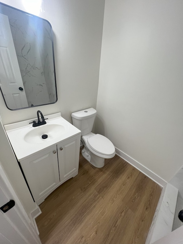 bathroom with hardwood / wood-style flooring, vanity, and toilet