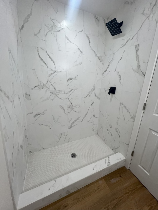 bathroom featuring hardwood / wood-style flooring and a tile shower