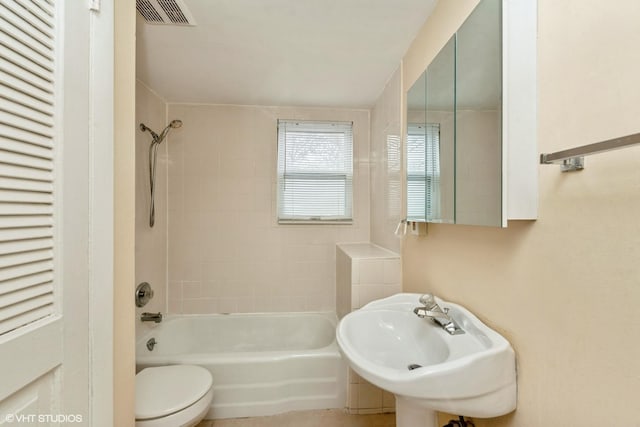 full bathroom with tiled shower / bath combo, sink, and toilet