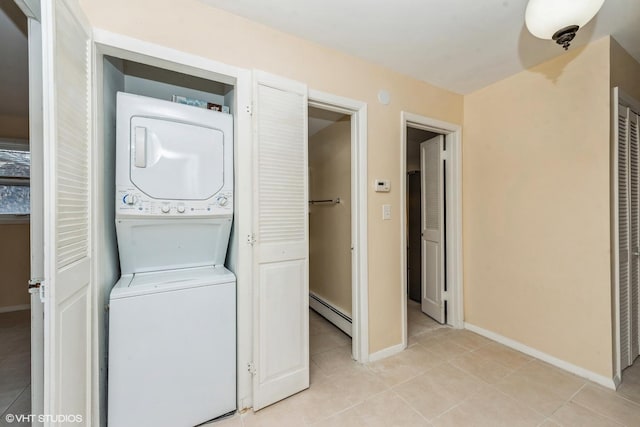 laundry area featuring a baseboard heating unit, light tile patterned floors, and stacked washer and clothes dryer