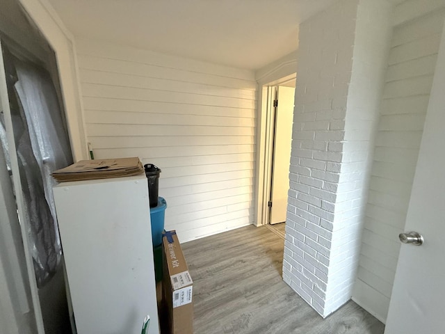 hall with wooden walls and light wood-type flooring