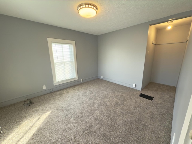 carpeted empty room featuring a textured ceiling