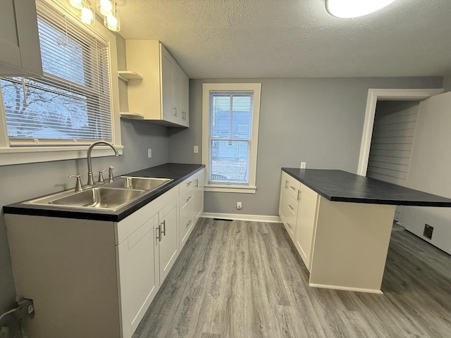 kitchen featuring sink, light hardwood / wood-style floors, kitchen peninsula, and white cabinets