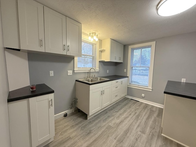 kitchen featuring sink, a textured ceiling, white cabinets, and light wood-type flooring