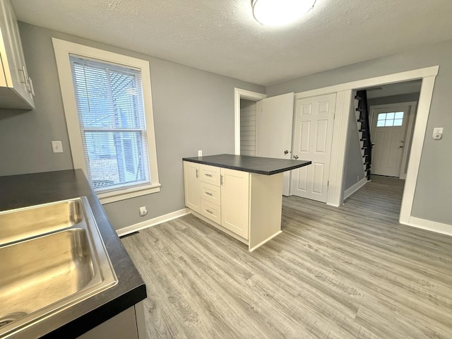 kitchen with white cabinetry, kitchen peninsula, sink, and light wood-type flooring