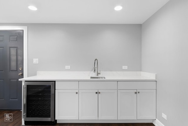 bar with dark wood-type flooring, sink, white cabinetry, beverage cooler, and light stone countertops