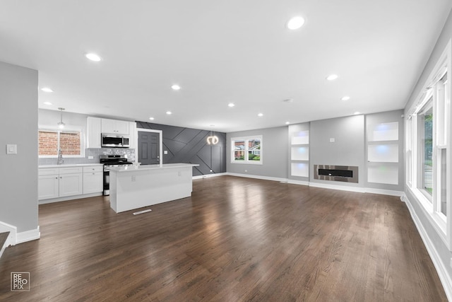 unfurnished living room featuring a healthy amount of sunlight, dark hardwood / wood-style floors, and sink