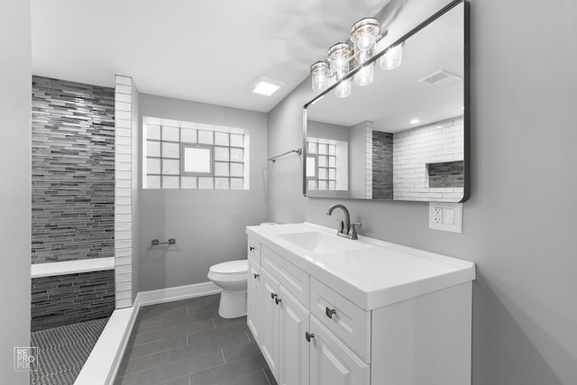 bathroom with vanity, tile patterned flooring, toilet, and tiled shower