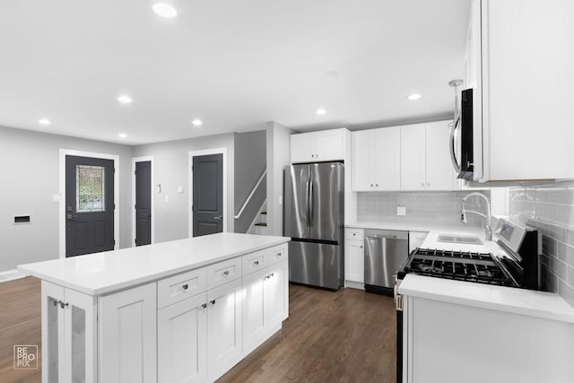 kitchen featuring a kitchen island, appliances with stainless steel finishes, sink, white cabinets, and dark wood-type flooring