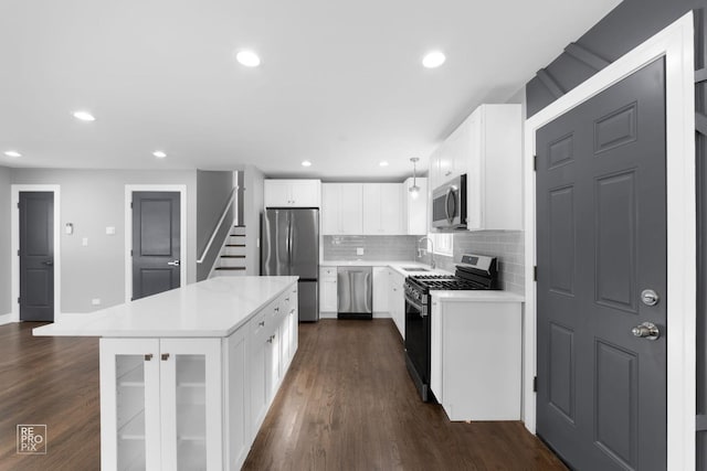 kitchen featuring appliances with stainless steel finishes, pendant lighting, sink, white cabinets, and a center island