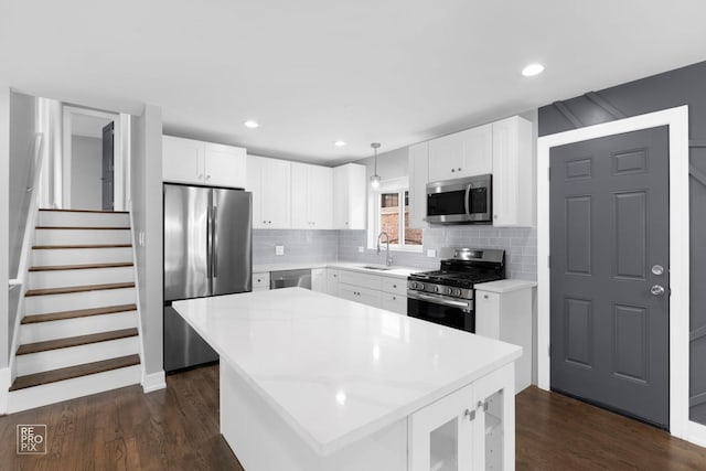 kitchen with sink, decorative light fixtures, a center island, appliances with stainless steel finishes, and white cabinets