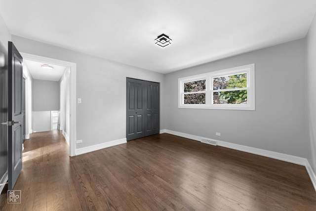 unfurnished bedroom with dark hardwood / wood-style flooring and a closet