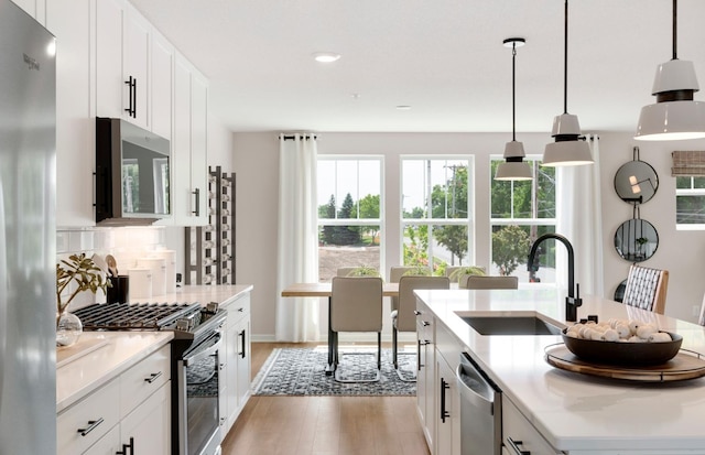 kitchen with white cabinets, tasteful backsplash, stainless steel appliances, and hanging light fixtures