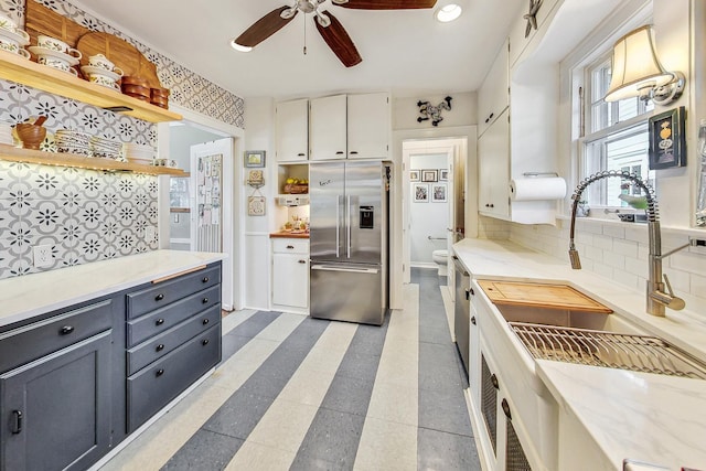 kitchen with high quality fridge, sink, white cabinets, decorative backsplash, and ceiling fan