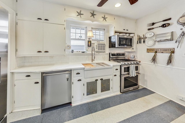 kitchen featuring sink, white cabinetry, appliances with stainless steel finishes, ceiling fan, and decorative backsplash