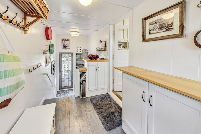 kitchen with dark wood-type flooring, wooden counters, and white cabinets