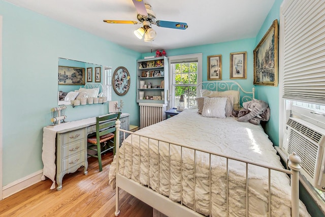 bedroom with ceiling fan, radiator heating unit, and light wood-type flooring