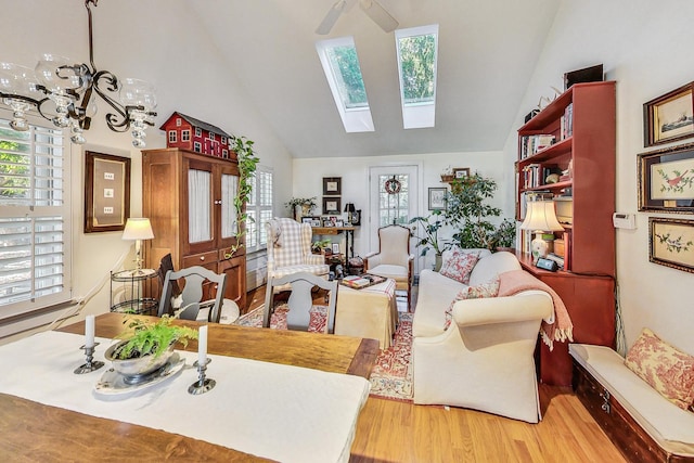 living room featuring hardwood / wood-style flooring, vaulted ceiling with skylight, and an inviting chandelier