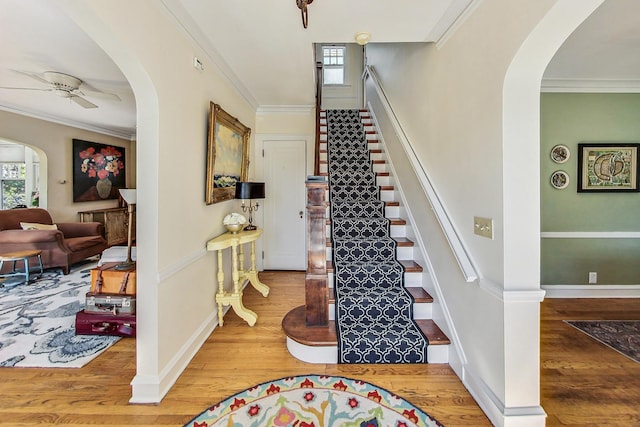 stairs with ornamental molding, plenty of natural light, and hardwood / wood-style floors