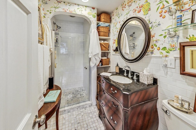 bathroom with an enclosed shower, vanity, toilet, and tile walls