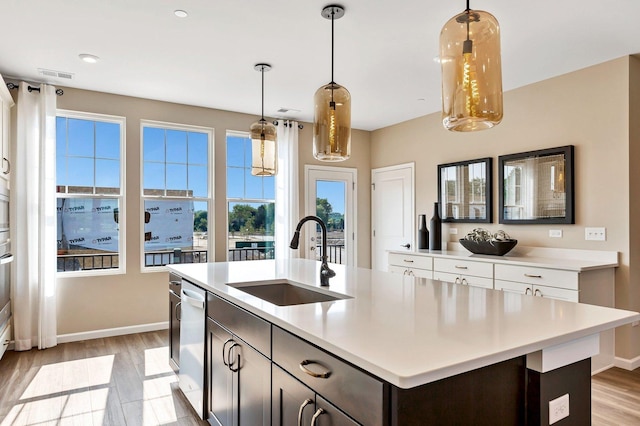 kitchen with pendant lighting, light hardwood / wood-style floors, sink, and dark brown cabinets