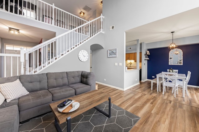 living room featuring an inviting chandelier, wood-type flooring, and a high ceiling