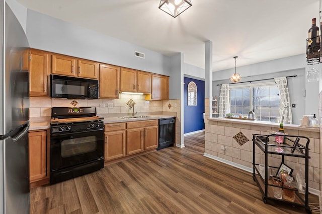 kitchen with dark wood-type flooring, sink, decorative light fixtures, black appliances, and backsplash