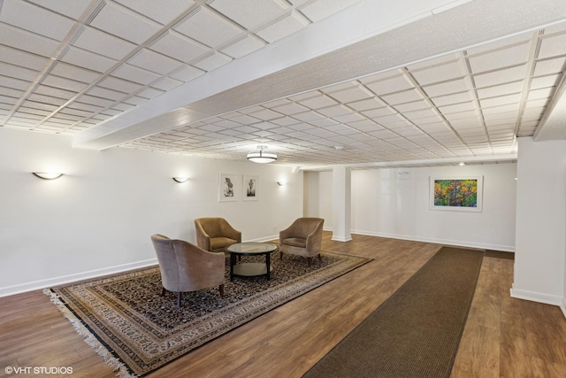 sitting room with a drop ceiling, baseboards, and wood finished floors