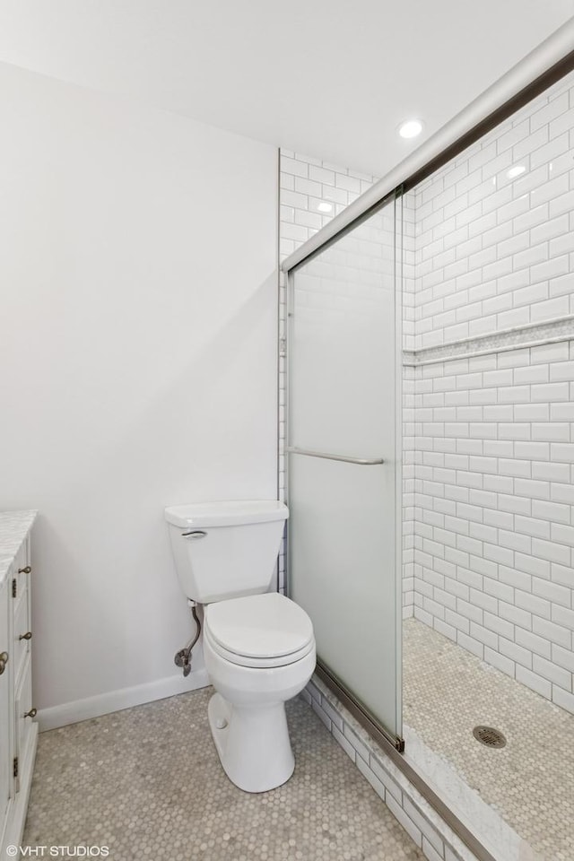 bathroom with tile patterned flooring, a shower stall, toilet, and baseboards