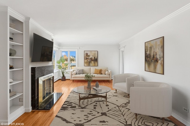 living room with baseboards, a baseboard radiator, a fireplace, light wood-style floors, and crown molding