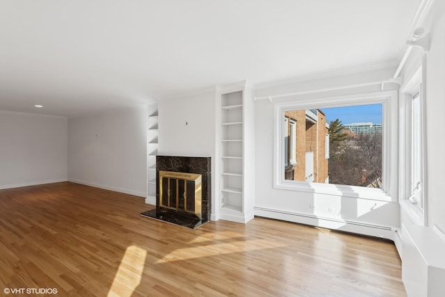 unfurnished living room featuring crown molding, wood finished floors, a high end fireplace, and a baseboard radiator