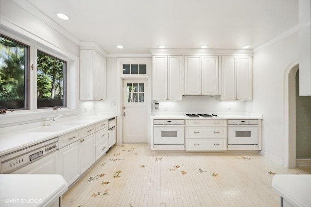 kitchen featuring sink, white appliances, light hardwood / wood-style flooring, white cabinetry, and ornamental molding