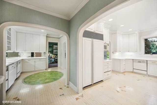 kitchen featuring crown molding, built in appliances, light hardwood / wood-style floors, white cabinets, and decorative backsplash