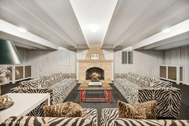 carpeted living room with wooden walls, a fireplace, and beam ceiling