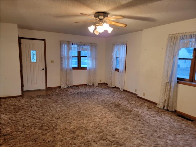 carpeted entrance foyer featuring ceiling fan and a textured ceiling