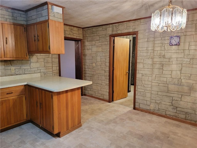 kitchen featuring pendant lighting, a notable chandelier, ornamental molding, and kitchen peninsula