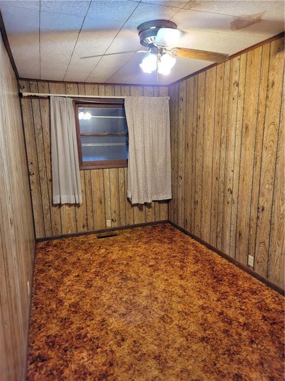 carpeted empty room featuring wooden walls