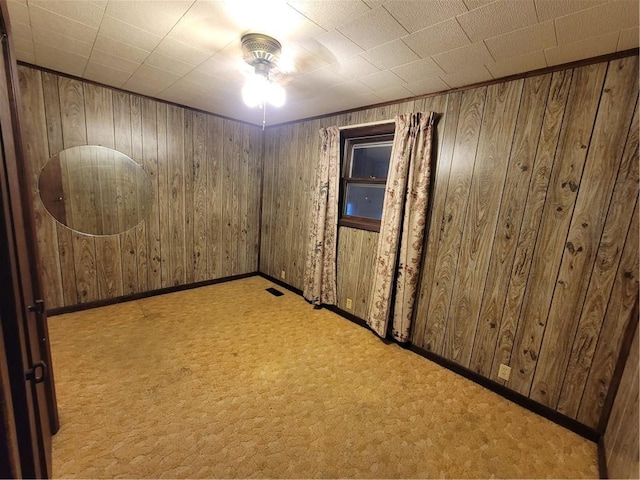 carpeted spare room featuring wooden walls