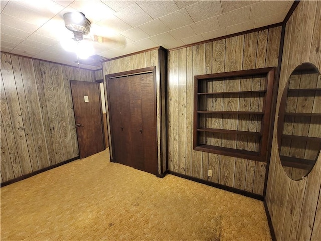 interior space featuring light colored carpet, a closet, and wood walls