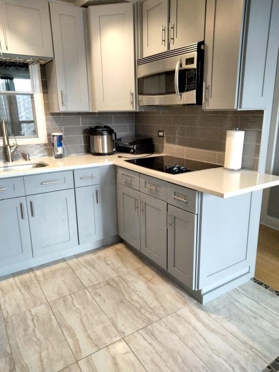 kitchen featuring sink, gray cabinets, tasteful backsplash, black electric cooktop, and kitchen peninsula