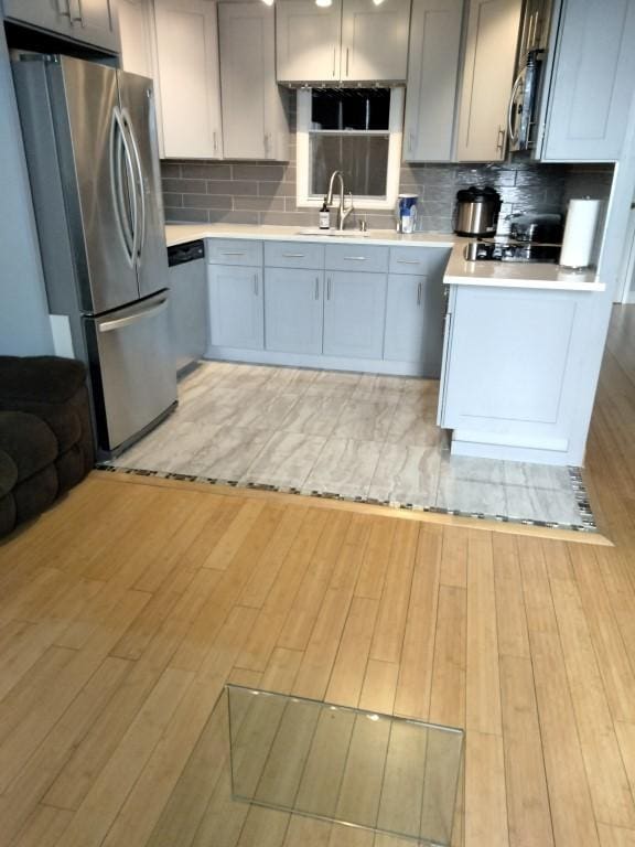 kitchen with tasteful backsplash, sink, gray cabinets, and stainless steel appliances