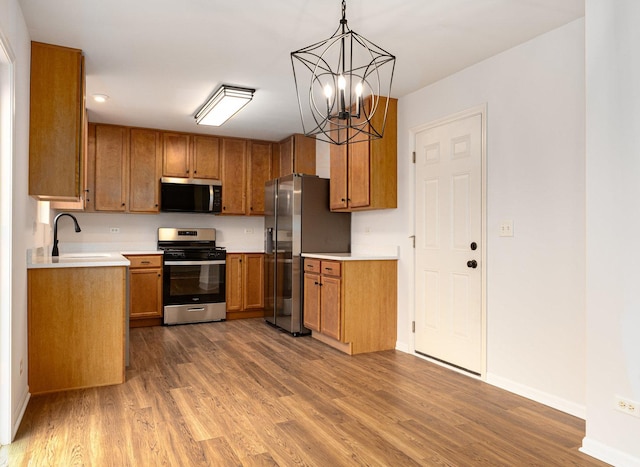 kitchen featuring pendant lighting, sink, dark wood-type flooring, an inviting chandelier, and stainless steel appliances