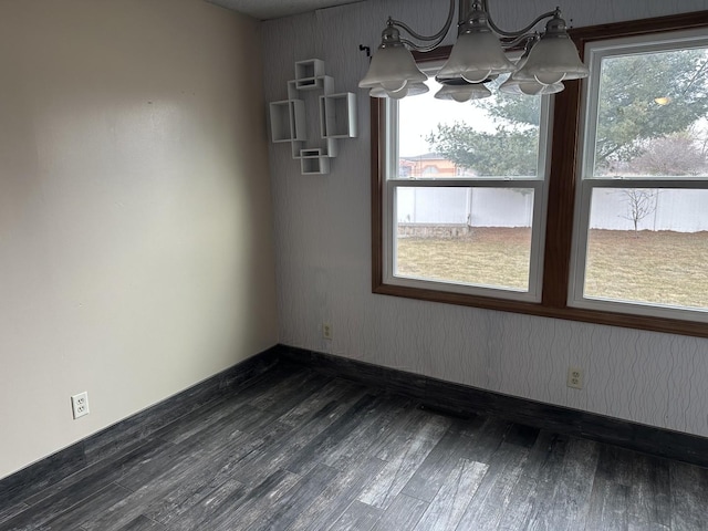 unfurnished dining area featuring dark wood-type flooring and a notable chandelier