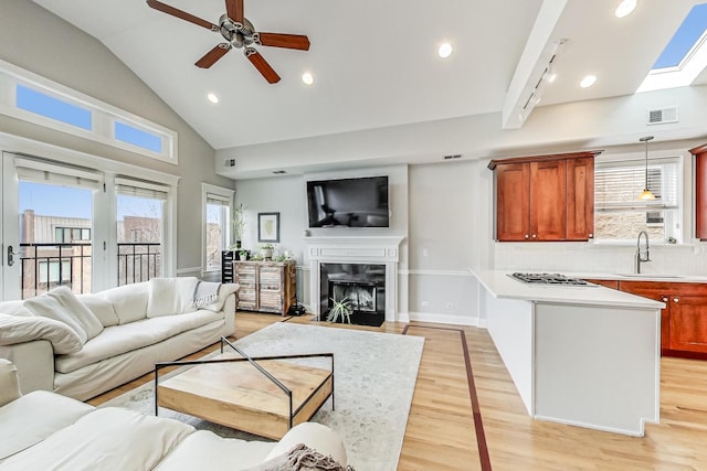 living room featuring ceiling fan, a wealth of natural light, sink, and light wood-type flooring