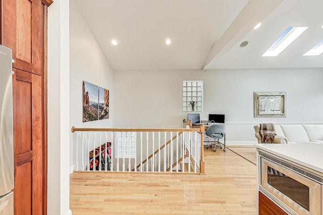 hall featuring lofted ceiling and light hardwood / wood-style flooring