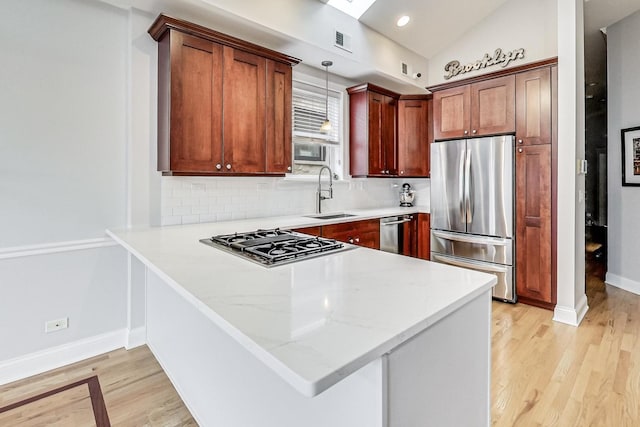 kitchen featuring decorative light fixtures, lofted ceiling, sink, light hardwood / wood-style floors, and stainless steel appliances