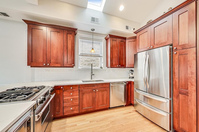 kitchen with sink, tasteful backsplash, decorative light fixtures, stainless steel appliances, and light hardwood / wood-style floors